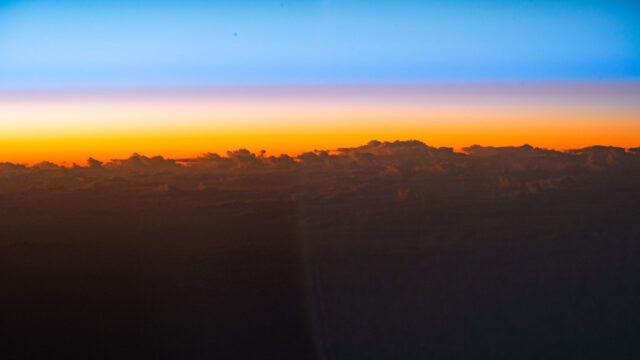 An orbital sunrise begins to illuminate the cloud tops